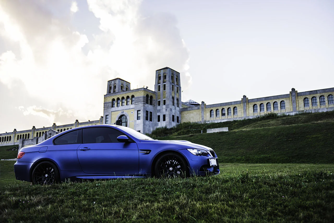 Automotive product shot of a blue performance coupe in front of a landmark building