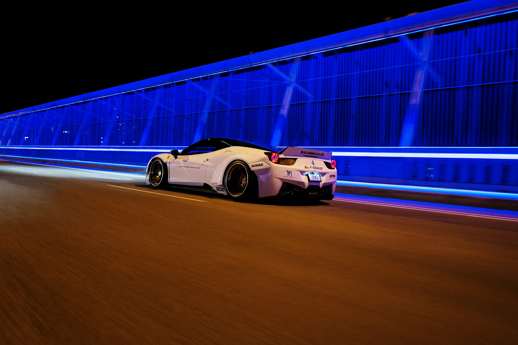 Night roller shot of a customized sports car on a blue-lit bridge, ideal for high-energy ads
